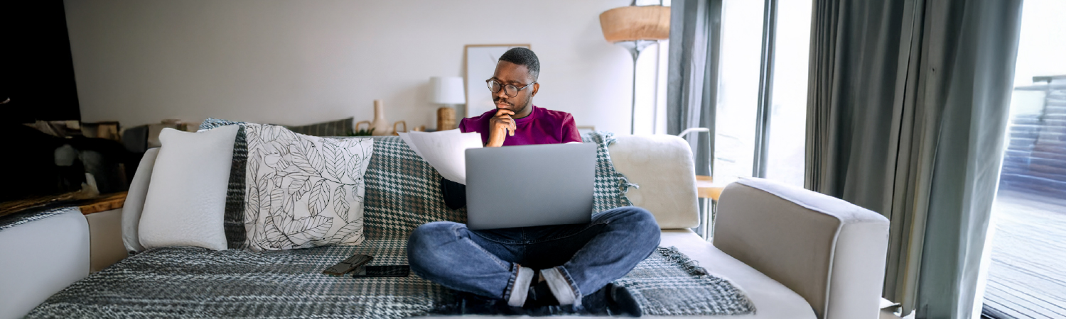 Person reading print and online document using laptop